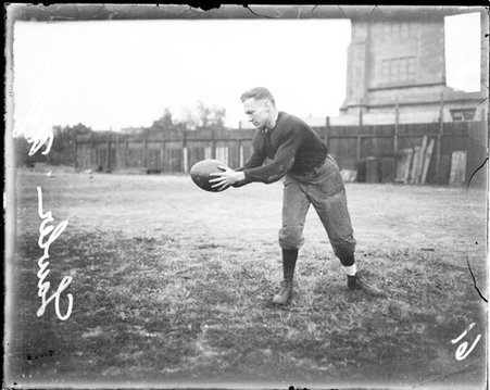University of Chicago football player Lawler holding a football out at his side on the field at Marshall Field - Chicago Daily News, Inc.