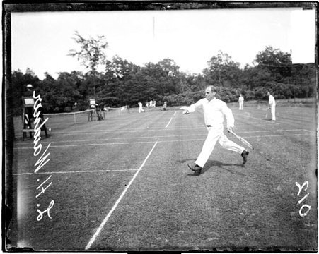 Tennis player L H Waidner holding a tennis racket with his left hand, moving forwards on a tennis court - Chicago Daily News, Inc.