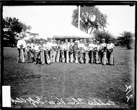 Caddies holding golf bags in front of them, standing in front of a canopy on the grounds of the Glen View Golf Club - Chicago Daily News, Inc.