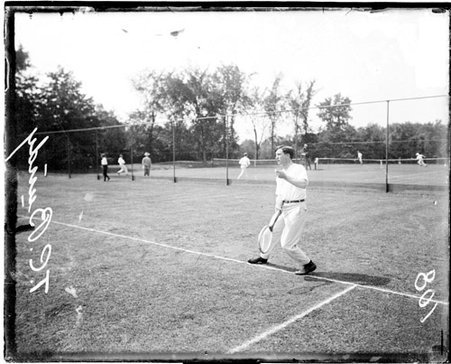 Tennis player Bundy holding a tennis racket with his right hand standing on the baseline on a tennis court - Chicago Daily News, Inc.