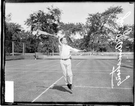 Tennis player J J Armstrong jumping and reaching in the air to hit a tennis shot on a tennis court - Chicago Daily News, Inc.