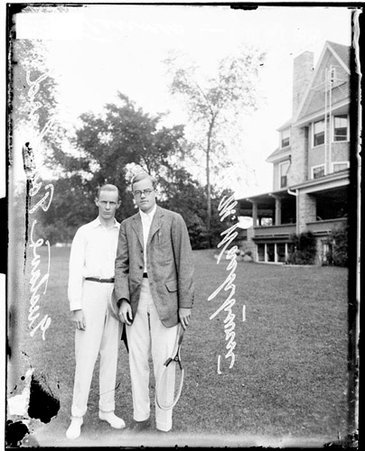 Tennis players Touchard and Washburn holding tennis rackets on a lawn in front of a building at the Onwentsia Club - Chicago Daily News, Inc.