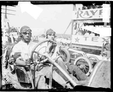 Automobile driver Hemming sitting in the driver's seat of an automobile parked in front of a tiered structure during an automobile race - Chicago Daily News, Inc.