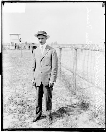 Jockey Allen Aubochon standing behind a railing on the side of a racetrack - Chicago Daily News, Inc.