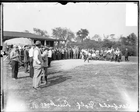 Unidentified golfer following through after swinging a golf club, in front of a building at the Garfield Park Golf Club - Chicago Daily News, Inc.