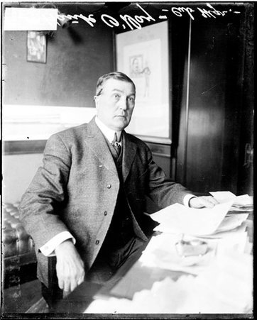 Baseball manager Hank O' Day, Cubs, sitting at a desk covered with papers in a room - Chicago Daily News, Inc.