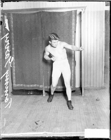 Boxer, Tommy Gary standing in front of a dark backdrop in a room - Chicago Daily News, Inc.