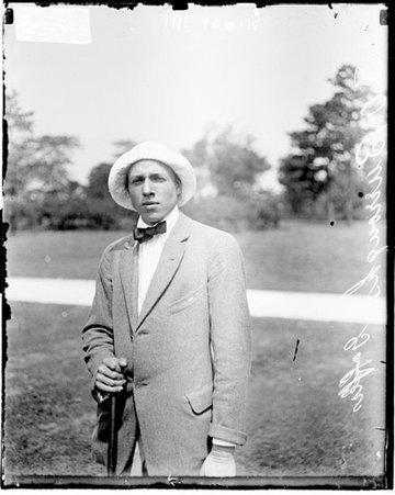 Golfer S. O. Burroughs resting his hand on the butt end of a golf club, standing on a grass area - Chicago Daily News, Inc.