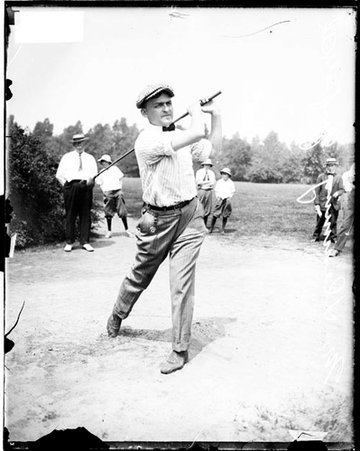 Golfer Demming following through after swinging a golf club, standing on the course at an unidentified golf club - Chicago Daily News, Inc.