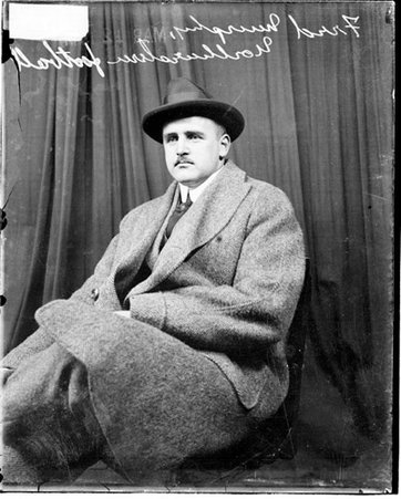 Northwestern University football coach Fred Murphy wearing street clothes, sitting in front of a dark backdrop in a room - Chicago Daily News, Inc.