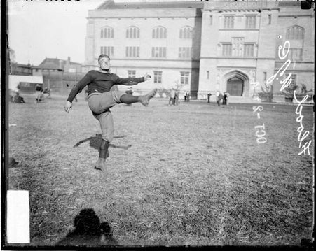 University of Chicago football player Flood following through after kicking a football, standing on the field at Marshall Field - Chicago Daily News, Inc.