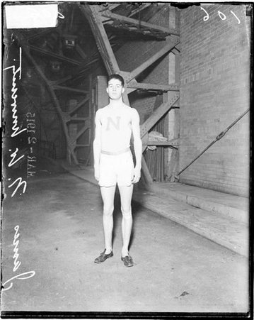 Athlete, Northwestern University, M. A. James standing inside building in front of brick wall - Chicago Daily News, Inc.