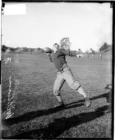 Northwestern University football player E P Williams cocking his arm to throw a football, standing on an athletic field - Chicago Daily News, Inc.