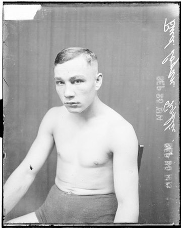 Pugilist Bud Logan sitting in front of a dark backdrop in a room - Chicago Daily News, Inc.