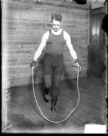 Pugilist, Jimmy Clabby, jumping rope in front of wood paneled wall - Chicago Daily News, Inc.