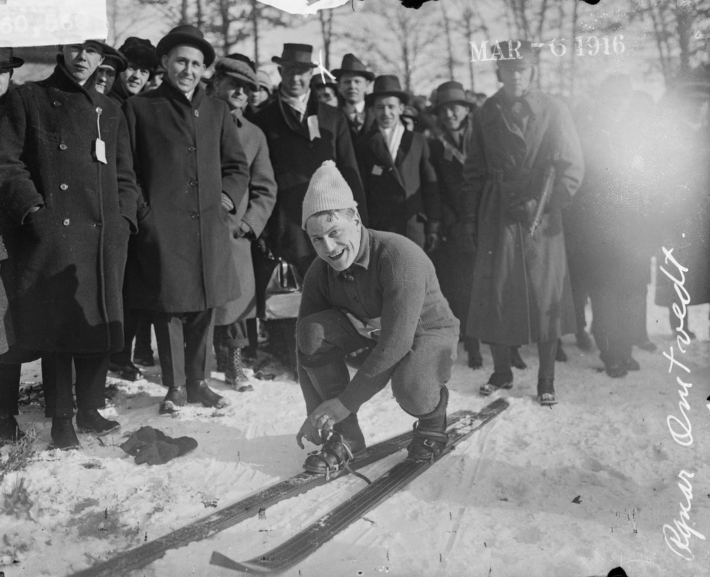 Skier, R. Omtvedt, fastening his skis in front of a crowd at a ski run - Chicago Daily News, Inc.