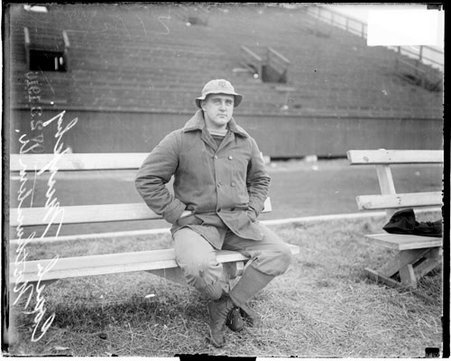 Football coach, Fred Murphy sitting on bench on sidelines of athletic field, Northwestern - Chicago Daily News, Inc.