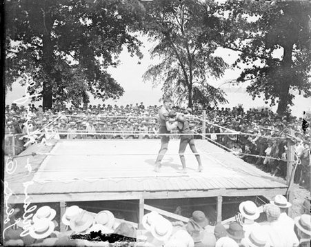 Boxing match, Jess Willard fighting a short statured opponent while a crowd watches - Chicago Daily News, Inc.