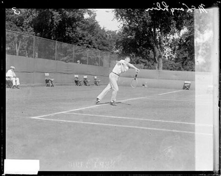 Tennis player, M. E. McLoughlin serving from behind baseline of tennis court - Chicago Daily News, Inc.