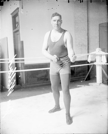 Pugilist, Jess Willard, standing in a boxing stance in the corner of a boxing ring - Chicago Daily News, Inc.