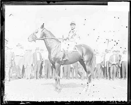 Jockey, Murphy posing atop race horse Dodge in front of spectators - Chicago Daily News, Inc.