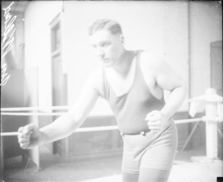 Pugilist, Jess Willard, right arm extended, warming up in an indoor ring - Chicago Daily News, Inc.