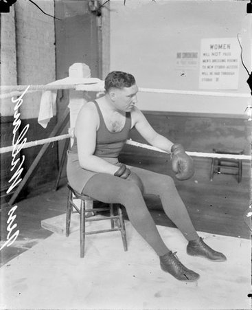 Pugilist, Jess Willard sitting in the corner of an indoor ring - Chicago Daily News, Inc.