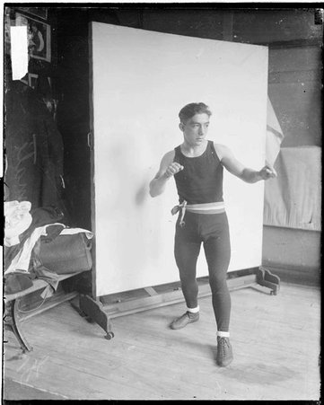 Athlete Frankie Jummati standing in a boxing stance in front of a light-colored backdrop in a room - Chicago Daily News, Inc.