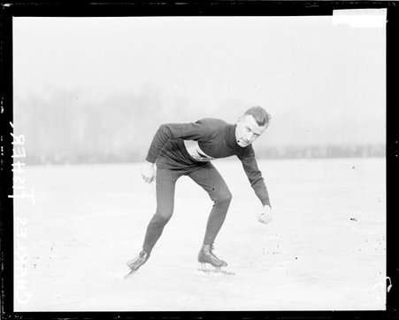 Ice skater Charles Fisher, crouching in a ready position on a frozen body of water - Chicago Daily News, Inc.
