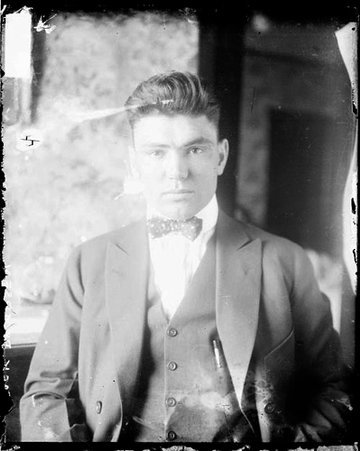Boxer, Jack Dempsey wearing a suit and facing the camera, sitting in a room - Chicago Daily News, Inc.