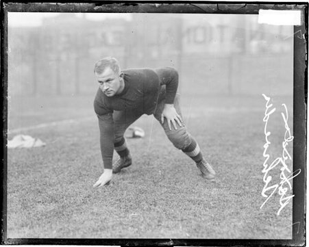 Football player Schroeder crouching in a ready position on a football field - Chicago Daily News, Inc.