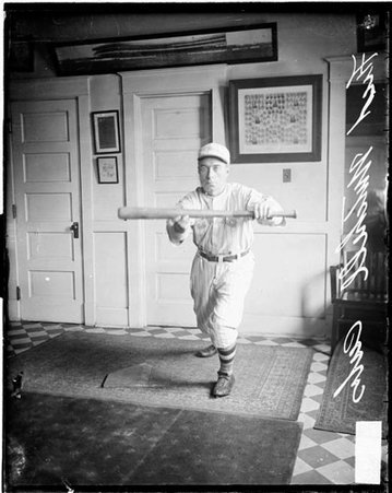 Baseball player Fred Mitchell, Cubs, leaning forward as if he is bunting a baseball, standing in front of a light-colored wall in a room - Chicago Daily News, Inc.