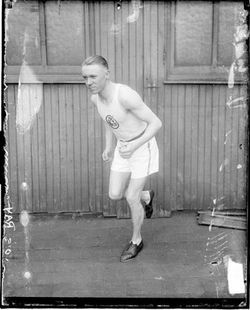 I. A. C. athlete J. W. Ray posing as if he is running in front a building - Chicago Daily News, Inc.