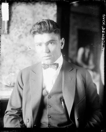 Boxer, Jack Dempsey wearing a suit and facing the camera, sitting in a room - Chicago Daily News, Inc.