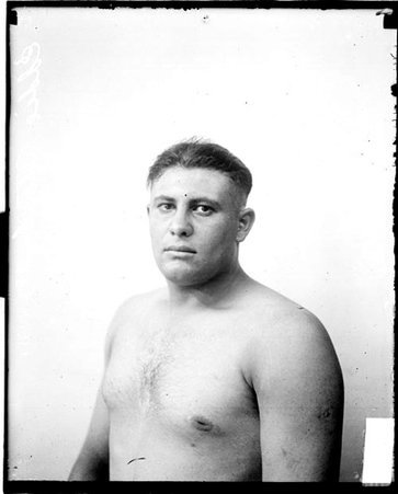 Pugilist, Eddie Stock sitting in front of a light-colored backdrop in a room - Chicago Daily News, Inc.