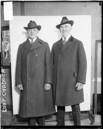 Wrestler Earl Caddock and an unidentified man standing in front of a light-colored backdrop in a room - Chicago Daily News, Inc.