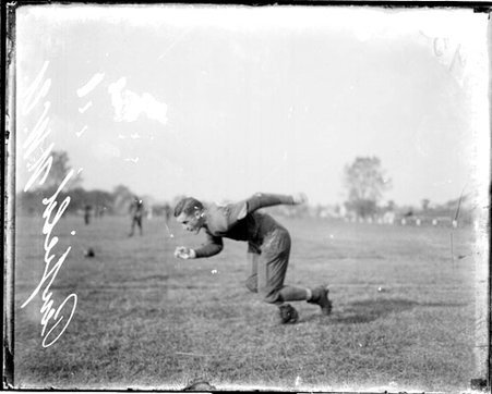 Northwestern University football player Penfield leaning forward and beginning to run on an athletic field in or near Evanston, Illinois - Chicago Daily News, Inc.