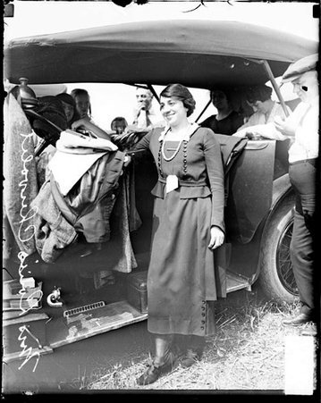 Mrs. Louise Chevrolet standing outdoors next to an automobile during Elgin auto races - Chicago Daily News, Inc.