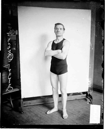 Swimmer, James Moran standing in front of a light-colored backdrop in a room - Chicago Daily News, Inc.