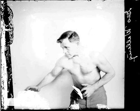 Boxer, Walling, standing in a boxing stance in front of a light-colored backdrop in a room - Chicago Daily News, Inc.
