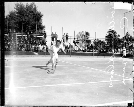 Tennis player, William Davis leaning forward and reaching with his tennis racket to hit a backhand shot - Chicago Daily News, Inc.
