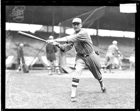 Unidentified baseball player following through after swinging a baseball bat, standing on a baseball field - Chicago Daily News, Inc.
