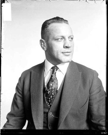 Wrestler, Harry Irslinger looking to his left, sitting in front of a light-colored backdrop in a room - Chicago Daily News, Inc.