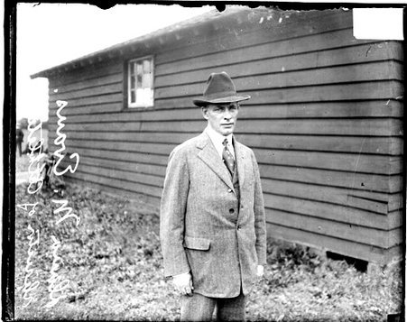 Athletic director Dana M. Evans, standing in front of a low wooden building - Chicago Daily News, Inc.