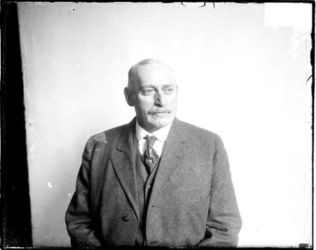 R. O. Heikes, sitting in front of a light-colored backdrop in a room - Chicago Daily News, Inc.