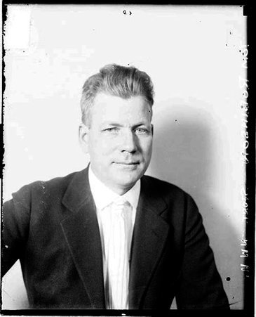 Tom Robinson, of Northwestern University, sitting in front of a light-colored backdrop in a room - Chicago Daily News, Inc.