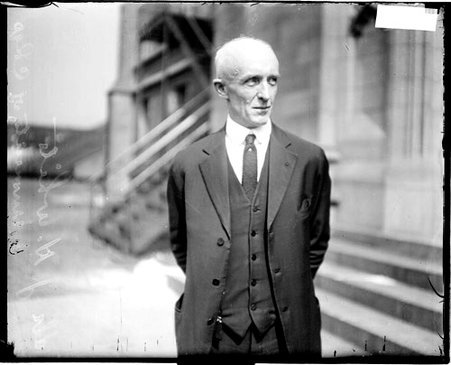 University of Chicago coach Dr. J. H. White looking to his left, standing in front of a building - Chicago Daily News, Inc.