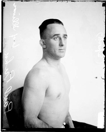 Wrestler, Paul Prehn facing to the right of the image, sitting in front of a light-colored backdrop in a room - Chicago Daily News, Inc.