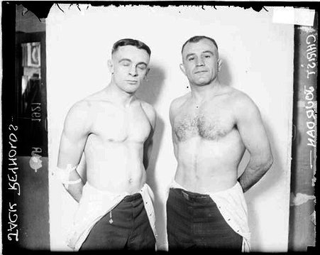 Wrestlers, Jack Reynolds and Chris Jordan, standing in front of a light-colored backdrop in a room - Chicago Daily News, Inc.