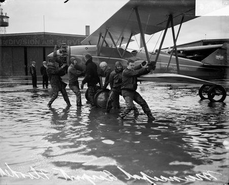 Men pulling an airplane in flooded airfield at Midway Airport - Chicago Daily News, Inc.